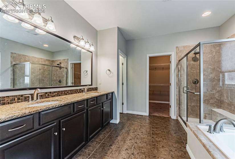 Bathroom featuring plus walk in shower, tile floors, large vanity, and double sink