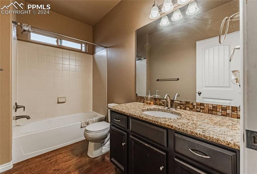 Full bathroom featuring hardwood / wood-style flooring, toilet, tiled shower / bath, and oversized vanity