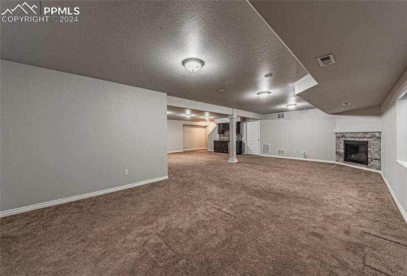 Basement with carpet, a stone fireplace, and a textured ceiling
