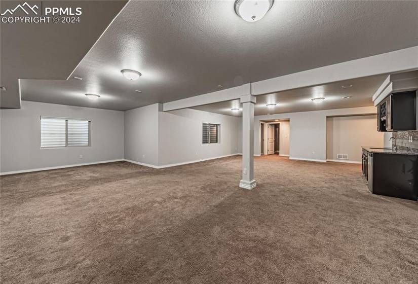 Basement featuring carpet floors, a textured ceiling, and sink