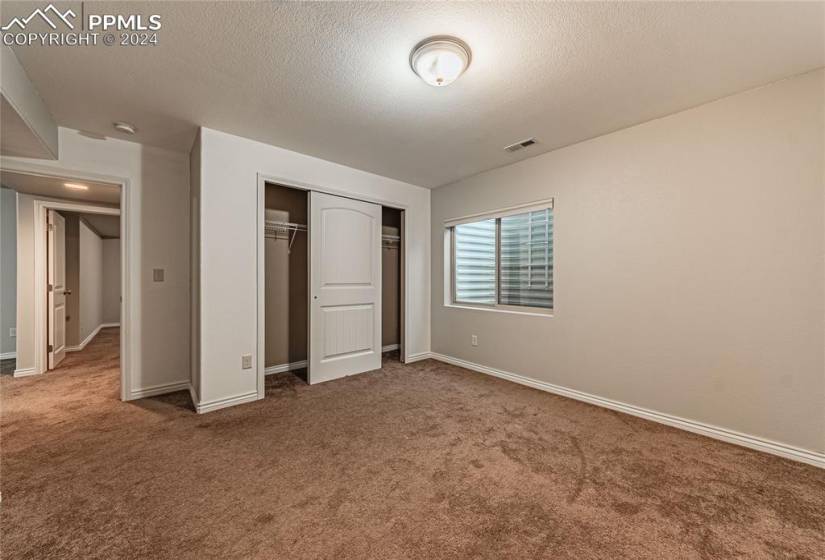 Unfurnished bedroom featuring a closet, a textured ceiling, and dark carpet