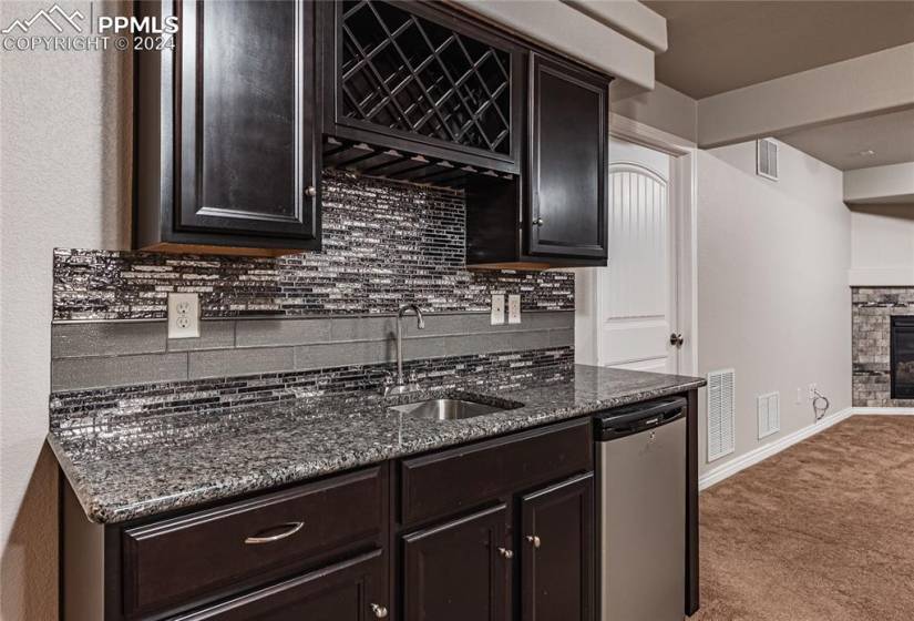Basement featuring a fireplace, backsplash, carpet, and stainless steel dishwasher