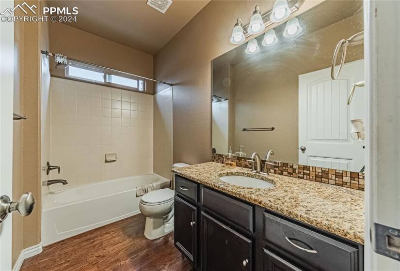 Full bathroom with tiled shower / bath, hardwood / wood-style flooring, toilet, and vanity
