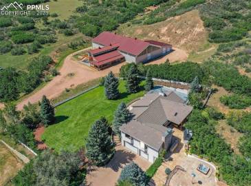 Luxury equestrian compound boasting modern ranch home on 13+ acres with custom built indoor riding arena, barn w/studio, & borders the USAFA.