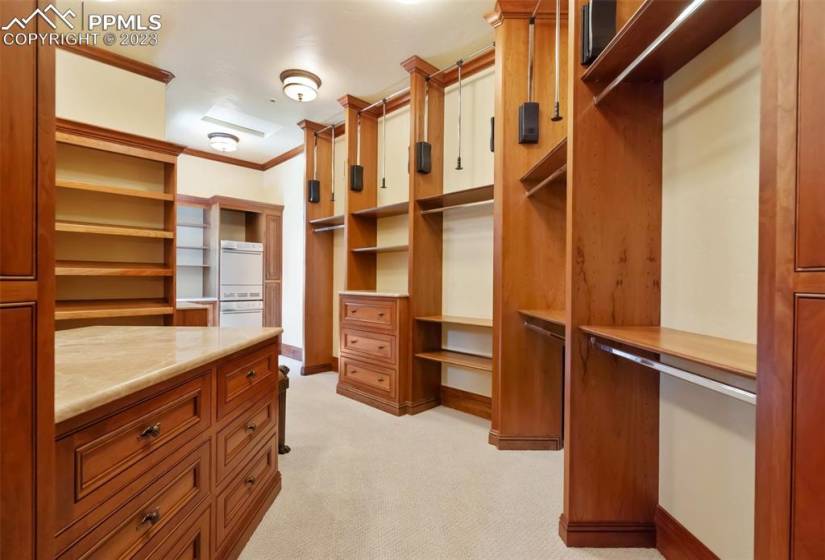 Spacious primary bedroom closet with custom built ins, island and secondary laundry