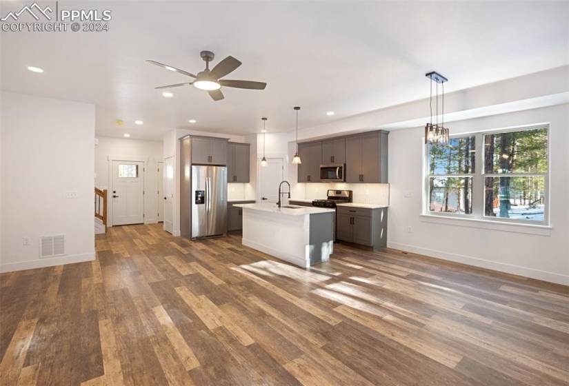 Unfurnished Kitchen featuring pendant lighting, stainless steel appliances, and a center island with sink
