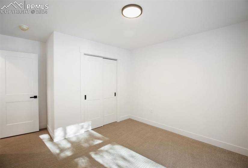Unfurnished bedroom three with a closet and light carpet