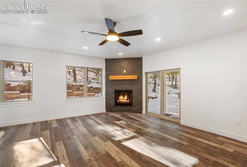 Unfurnished living room with dark wood-type flooring, a fireplace, and ceiling fan