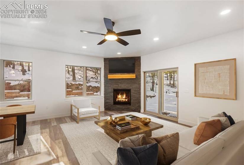 Virtually staged: Living room featuring LVP flooring, a healthy amount of sunlight, a fireplace, and ceiling fan