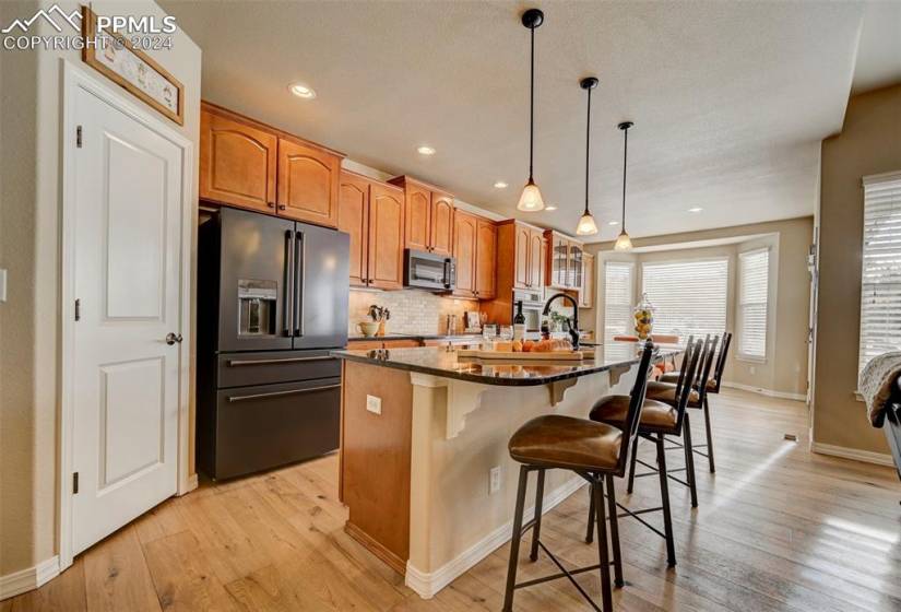 Kitchen featuring light hardwood / wood-style flooring, a breakfast bar, stainless steel appliances, and a kitchen island with sink