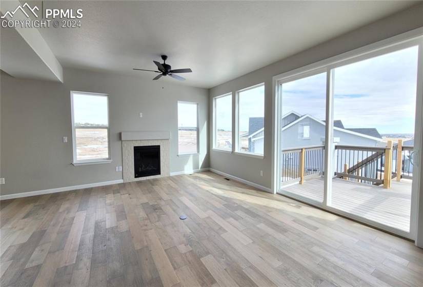 Great room with engineered wood flooring, floor outlet, ceiling fan, gas fireplace with beautiful tile surround, and walk out to the composite deck!