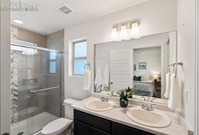 Bathroom with walk in shower, large vanity, double sink, and toilet