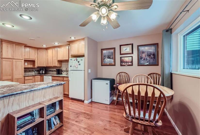 Kitchen featuring light brown cabinets, ceiling fan, tasteful backsplash, white appliances, and light wood-type flooring