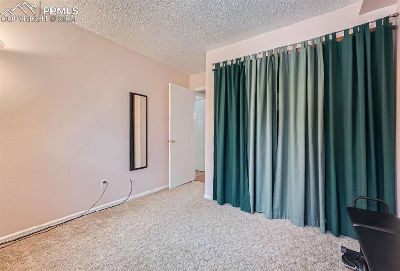 Unfurnished bedroom featuring a textured ceiling and carpet floors
