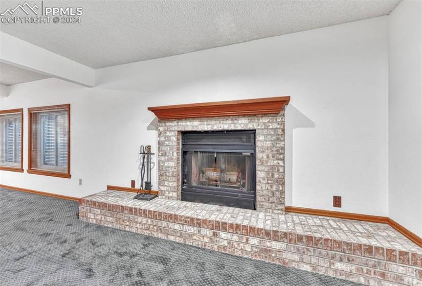 Basement wood fireplace with brick surround, raised hearth, and mantle.