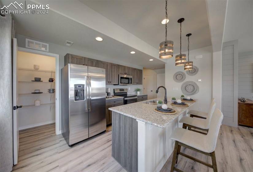 Kitchen featuring light hardwood / wood-style flooring, a kitchen island with sink, a breakfast bar area, sink, and stainless steel appliances