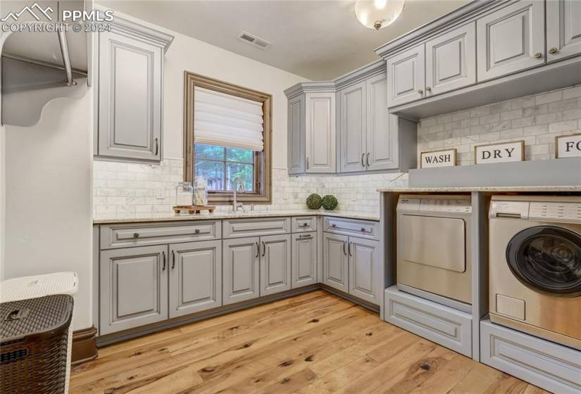 Laundry on upper level includes marble countertops, built in cabinetry, utility sink