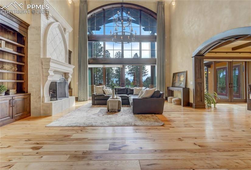 View upon entering will take your breath away! Great room with Expansive windows, cast limestone mantle, built-in cabinetry, vaulted ceiling with exposed wood trussed and custom iron motorized chandelier