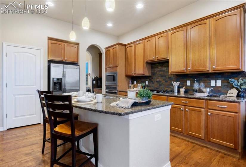 Appliances include a stainless steel refrigerator, gas cooktop, builtin oven, microwave, and dishwasher.