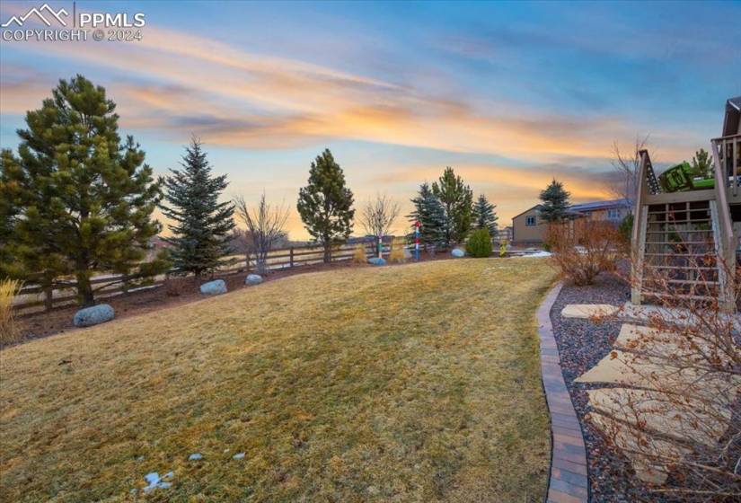 0.32 acre fenced lot with mature trees for privacy, manicured lawn with auto sprinklers, and stairs to the composite deck.