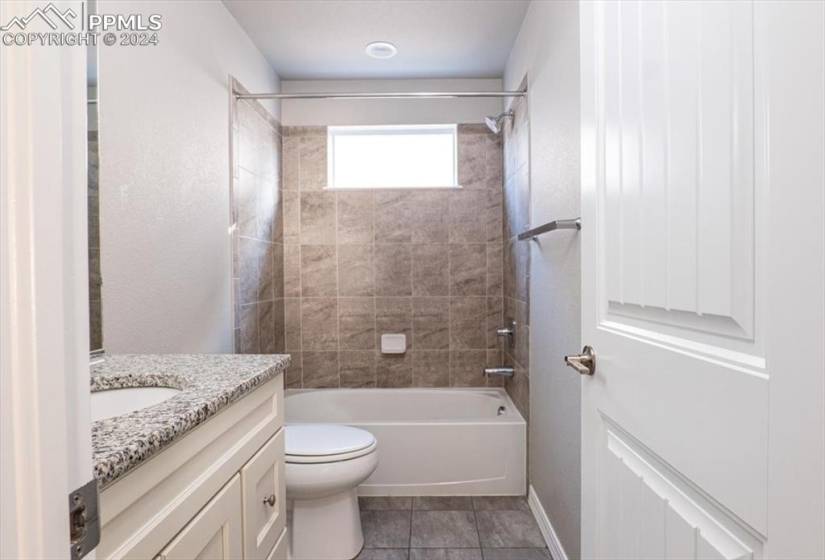 Upstairs full bathroom featuring tiled shower / bath combo, toilet, vanity, and tile flooring