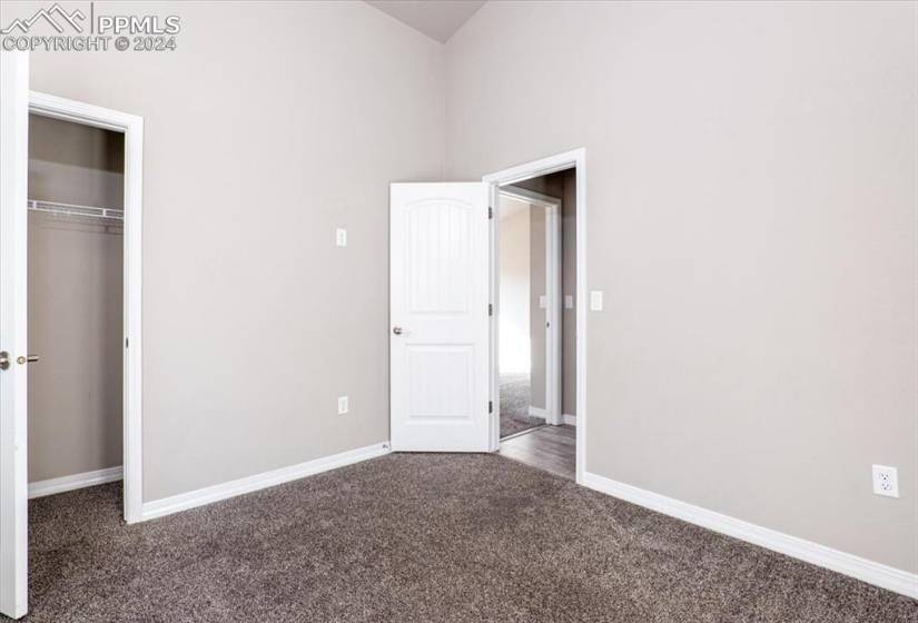 Upstairs bedroom featuring a closet, dark colored carpet, and a high ceiling