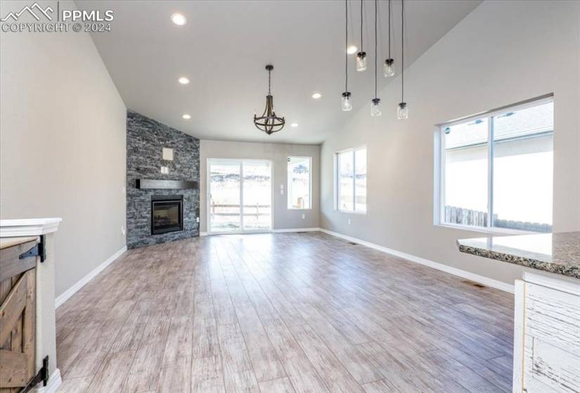 Living/family room featuring a fireplace, light wood-type flooring, and high vaulted ceiling