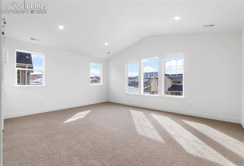 Spare room with light carpet and vaulted ceiling