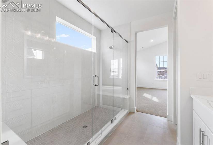Bathroom featuring a wealth of natural light, vanity, tile flooring, and a shower with shower door