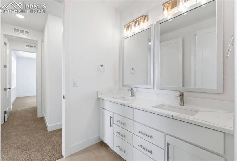 Bathroom with tile floors, double sink, and vanity with extensive cabinet space