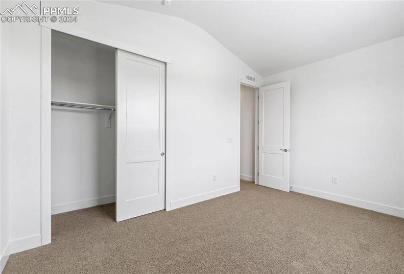 Unfurnished bedroom with a closet, carpet floors, and lofted ceiling