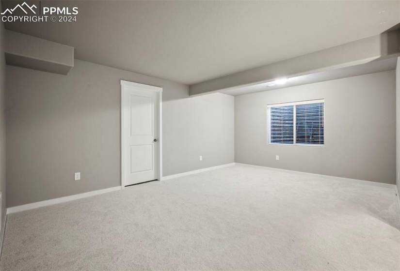 Space for a pool table or movie area in the basement with finished storage behind the door.