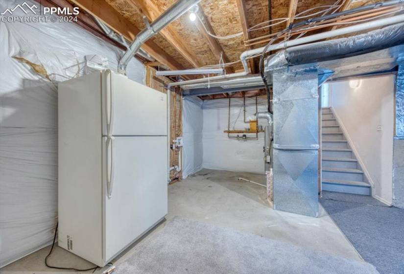 Unfinished Basement with white refrigerator that stays