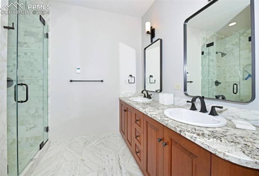 Bathroom featuring double vanity, a shower with door, and tile flooring