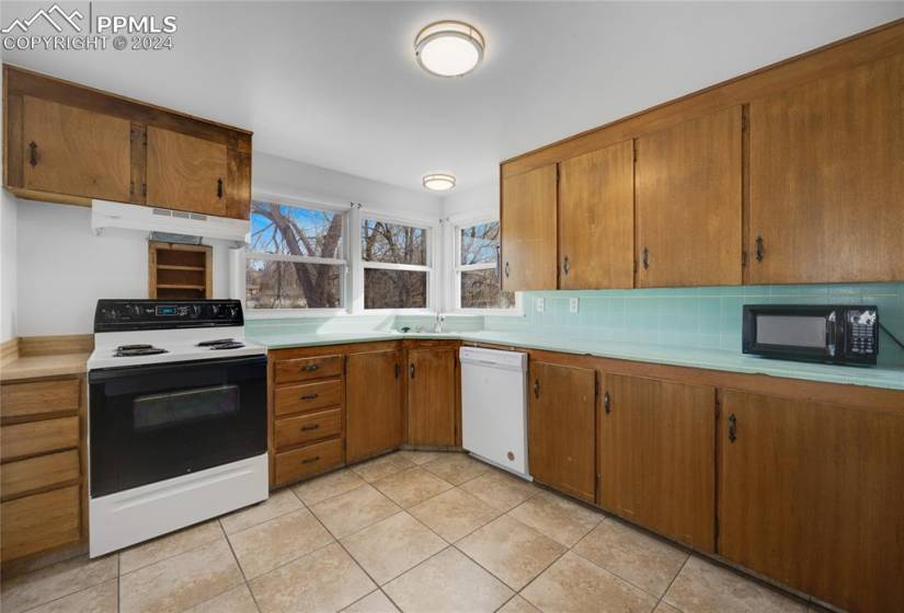 Kitchen with white appliances, light tile flooring, and backsplash