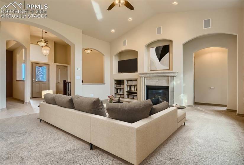 Virtually staged living room with built-ins, gas fireplace, and wall-to-wall windows.