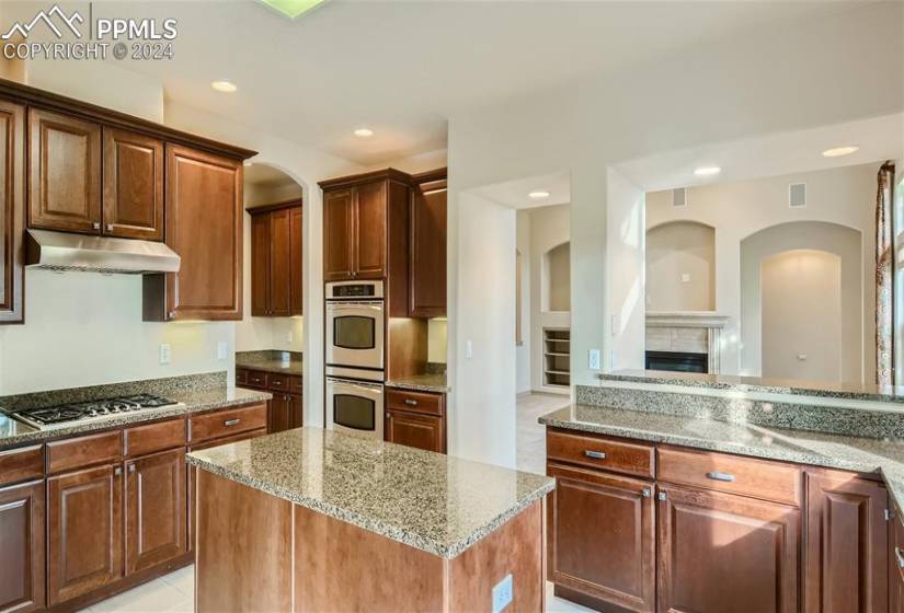 Gourmet kitchen with granite, stainless appliances, double ovens, upgraded cabinetry, bar, and island.