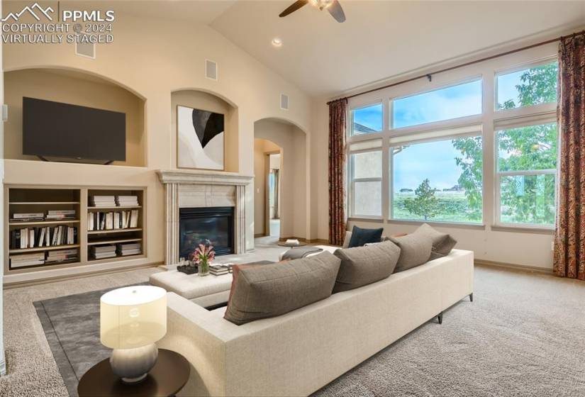 Virtually staged living room with built-ins, gas fireplace, and wall-to-wall windows.