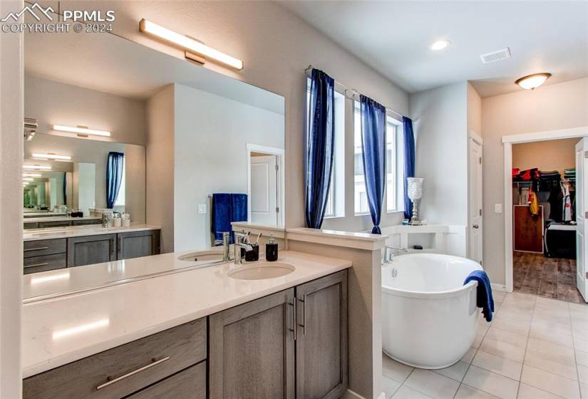 Bathroom featuring a tub, vanity, and tile flooring