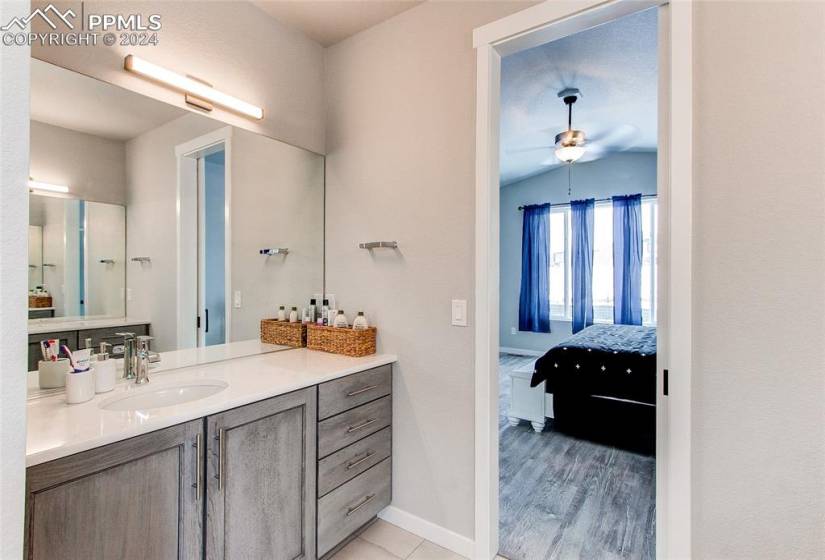 Bathroom with hardwood / wood-style floors, vanity, ceiling fan, and lofted ceiling
