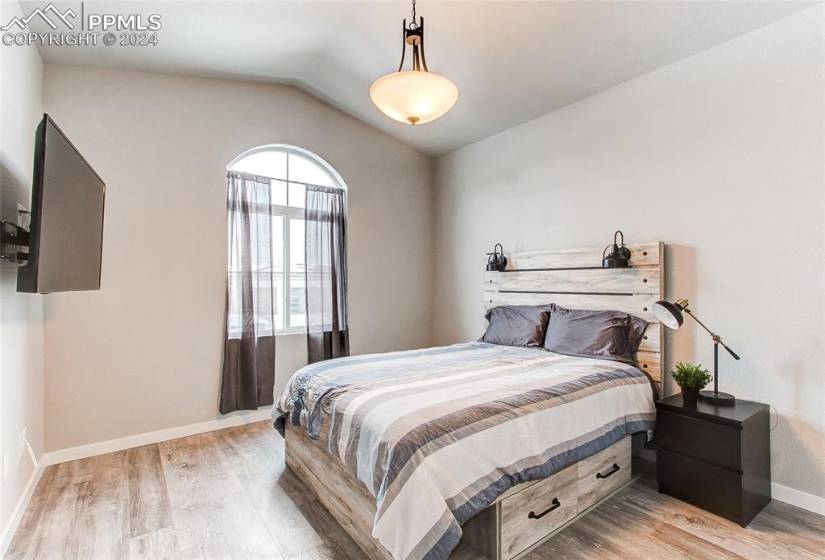 Bedroom featuring multiple windows, vaulted ceiling, and light hardwood / wood-style floors