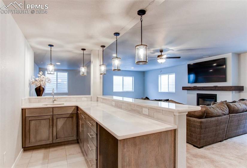 Kitchen with kitchen peninsula, sink, decorative light fixtures, light tile floors, and ceiling fan