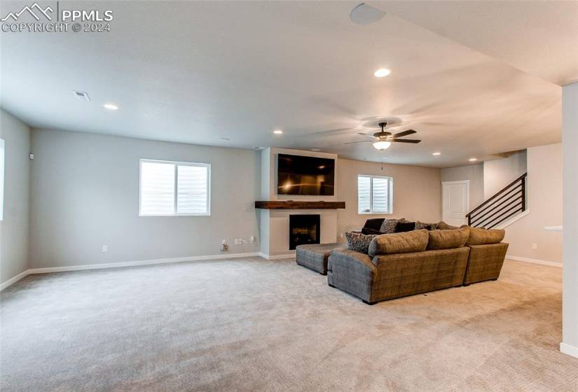 Living room with a fireplace, a wealth of natural light, ceiling fan, and light colored carpet