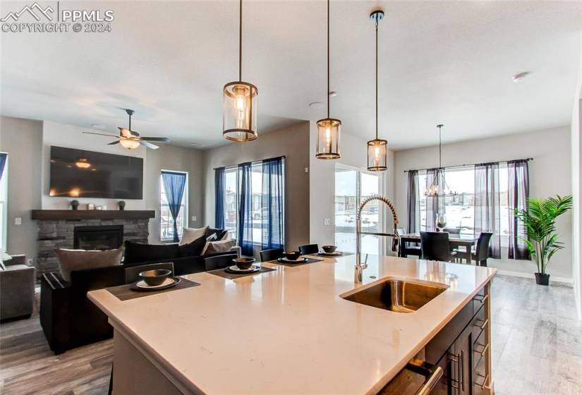 Kitchen with a fireplace, light hardwood / wood-style floors, hanging light fixtures, and sink