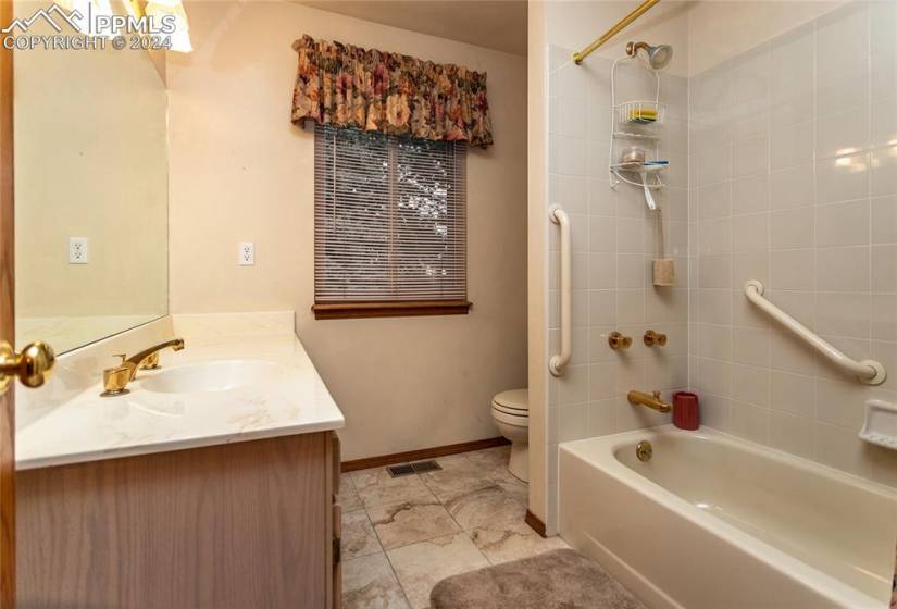 Full bathroom featuring tile floors, tiled shower / bath combo, vanity, and toilet.