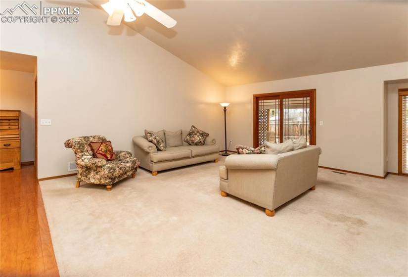 Living room featuring light carpet, high vaulted ceiling, and ceiling fan.