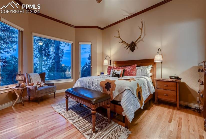 Primary bedroom with light wood flooring and ornamental molding