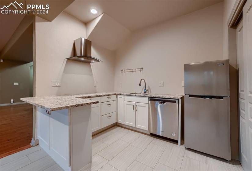 Lower level Kitchenette with white cabinetry, kitchen peninsula, appliances with stainless steel finishes and pantry