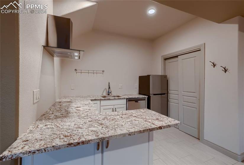 Lower level Kitchenette with white cabinetry, kitchen peninsula, appliances with stainless steel finishes and pantry