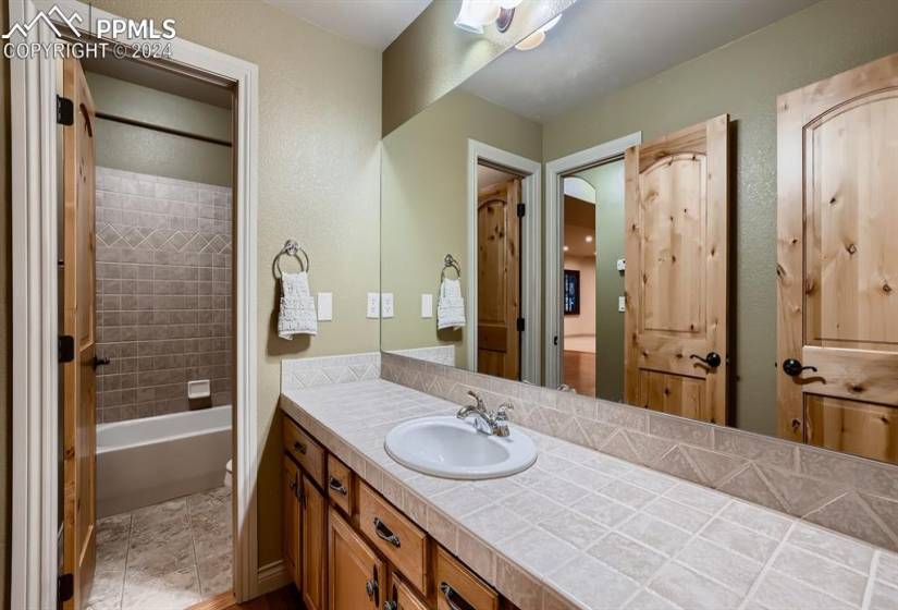 Lower level bathroom featuring vanity, tiled shower / bath, and tile flooring